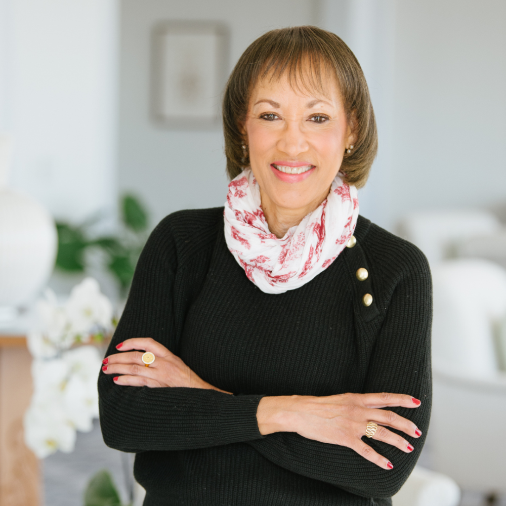 Olivia Branch smiling with arms crossed in a stylish outfit