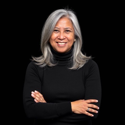 Genevieve Villaflor, a woman with graying hair, smiles confidently.