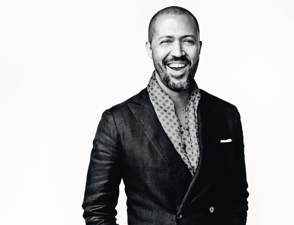 Cord Jefferson smiling in a suit with a patterned scarf.