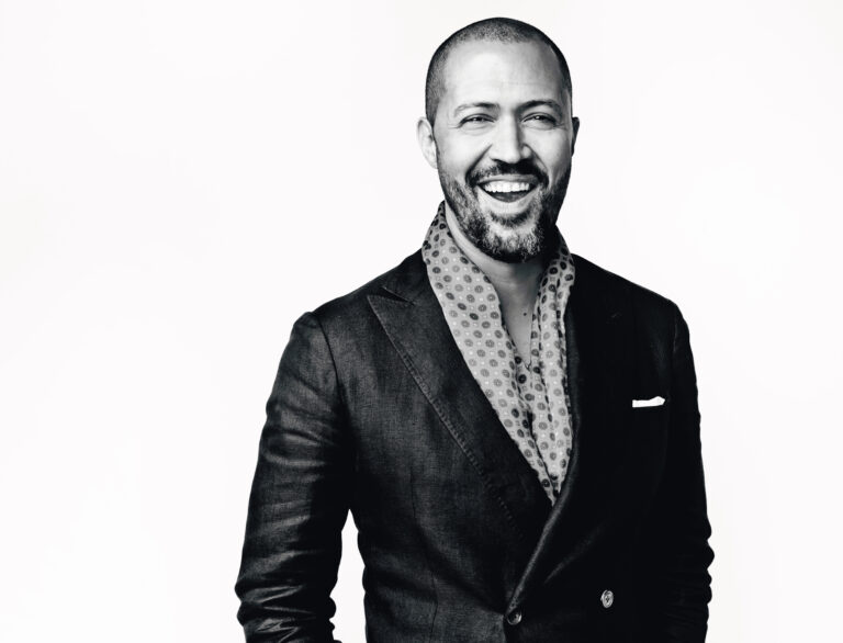 Cord Jefferson smiling in a suit with a patterned scarf.