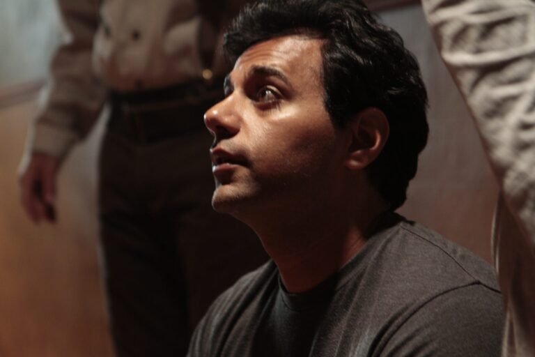 Dylan Narang looks upward, with two other people standing near him.