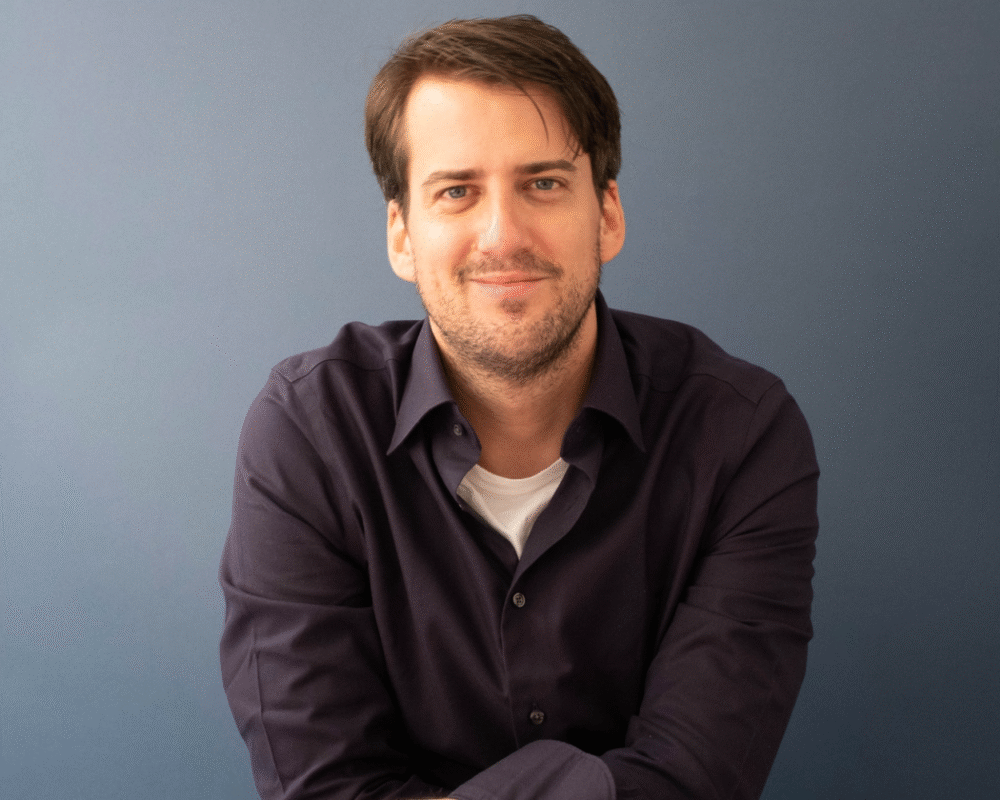 Portrait of Scott Ruderman, smiling against a blue background.