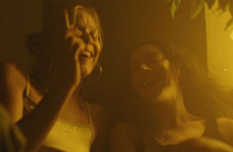 Two friends laughing in warm, golden light.