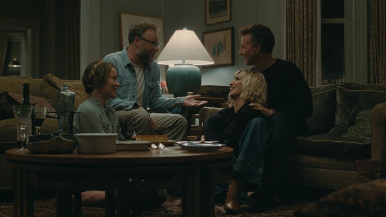 Four people gathered in a living room, two couples talking and laughing.