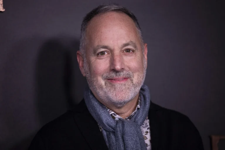 Man with a beard and a scarf smiles at the camera.