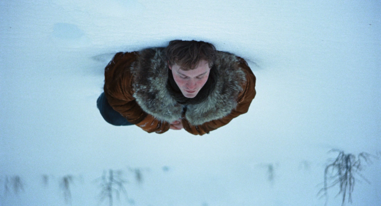 Man in fur-lined coat standing in deep snow during a long winter