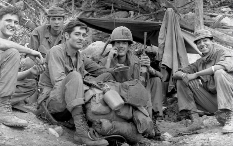 Five soldiers in uniform rest in a field, a price paid in war.