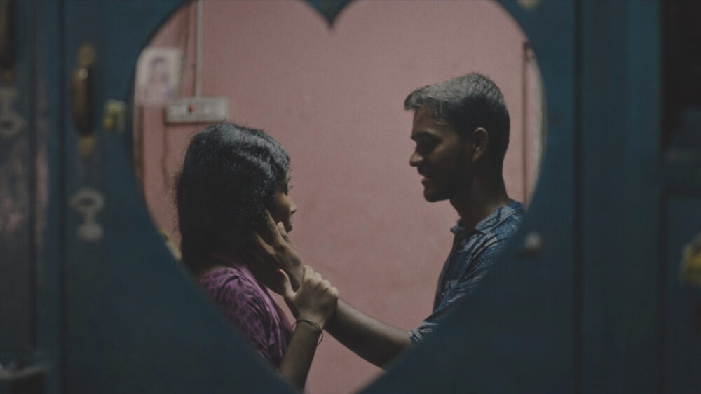 A young couple shares an intimate moment framed by a heart-shaped mirror in Delupi.