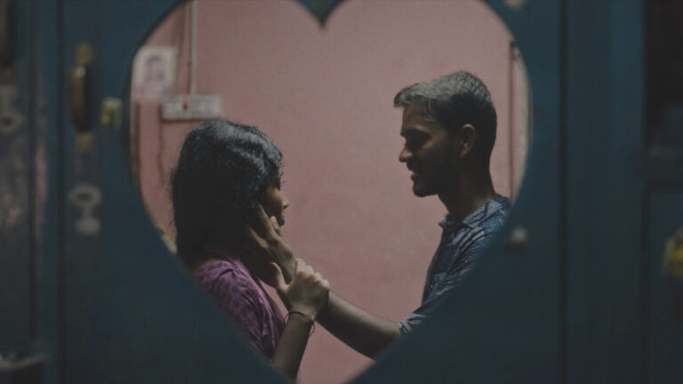A young couple shares an intimate moment framed by a heart-shaped mirror in Delupi.