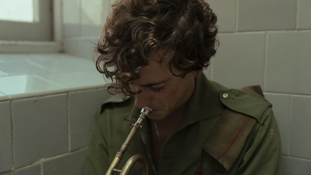 Musician in military uniform plays a trumpet in a tiled room