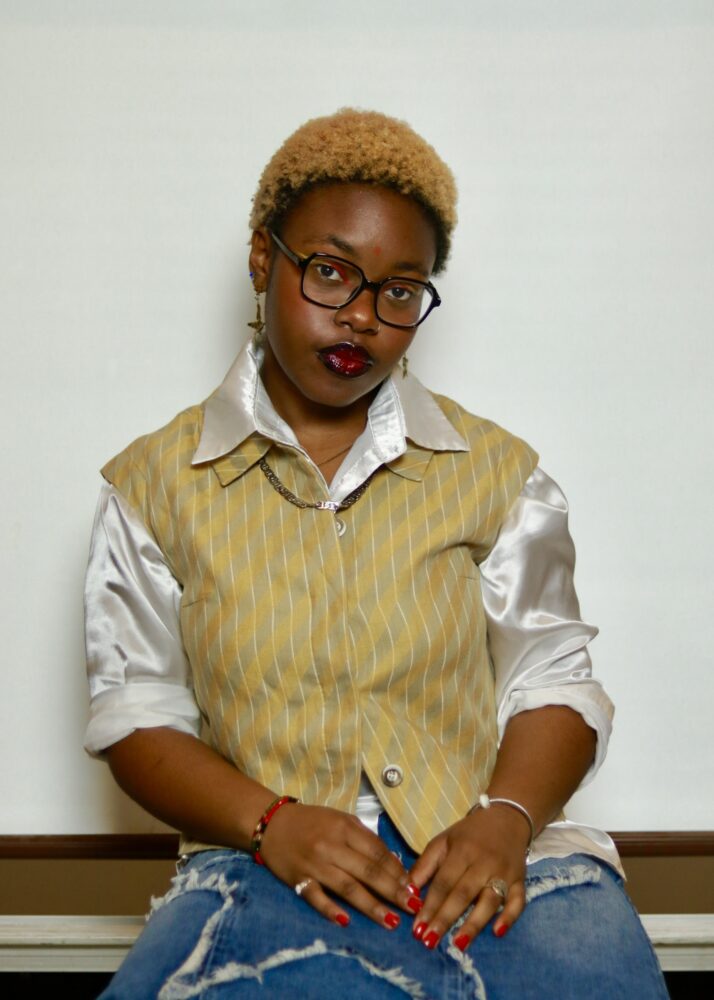 Nailah Hill, a stylish Black woman with blonde hair and glasses, poses confidently.