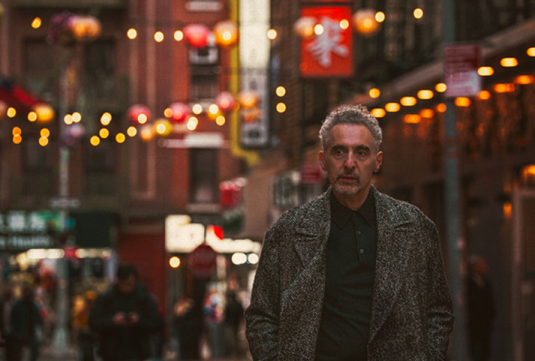 Man in Chinatown, New York, with blurry lights and people in the background