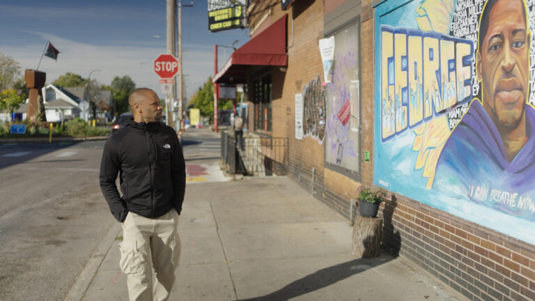 Man walks past George Floyd mural, a community canvas.