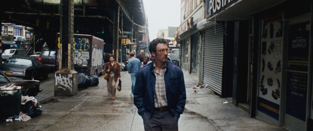 Man walks down a gritty New York street, reflecting the urban decay.