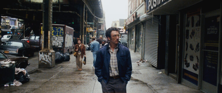 Man walks down a gritty New York street, reflecting the urban decay.