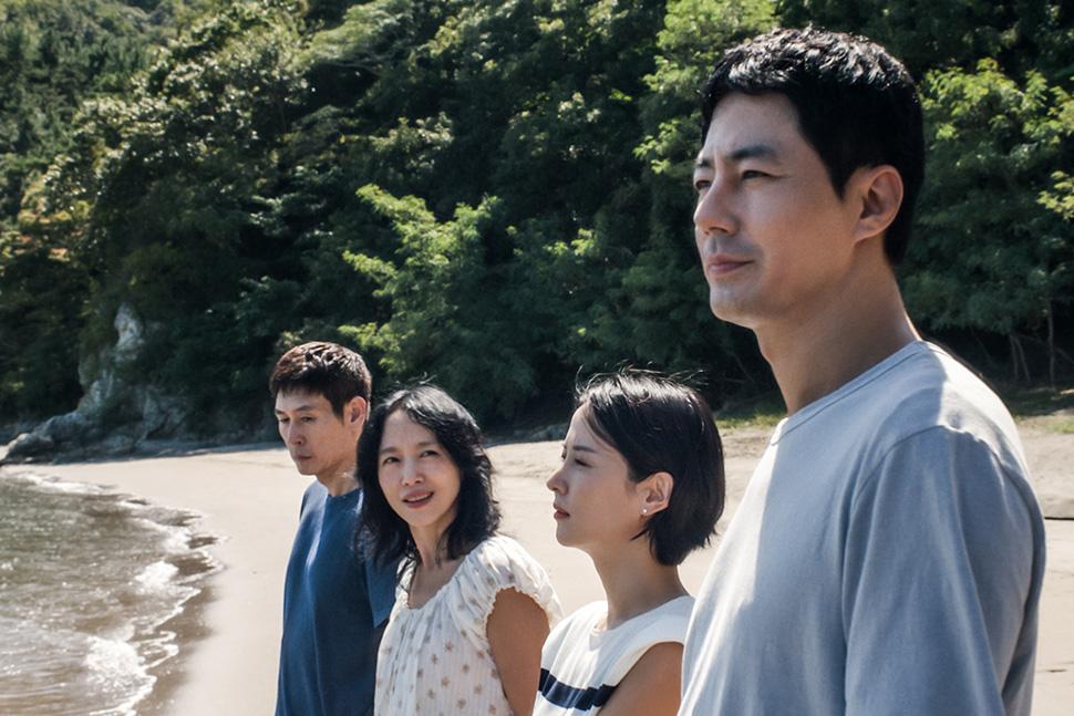 Four people stand on a beach with trees in the background, possibly a scene from "Possible Love.
