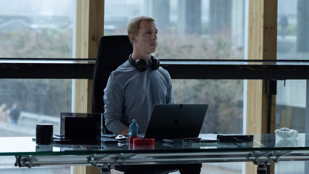 Man with headphones sits at desk with laptop, reflecting the social reckoning.