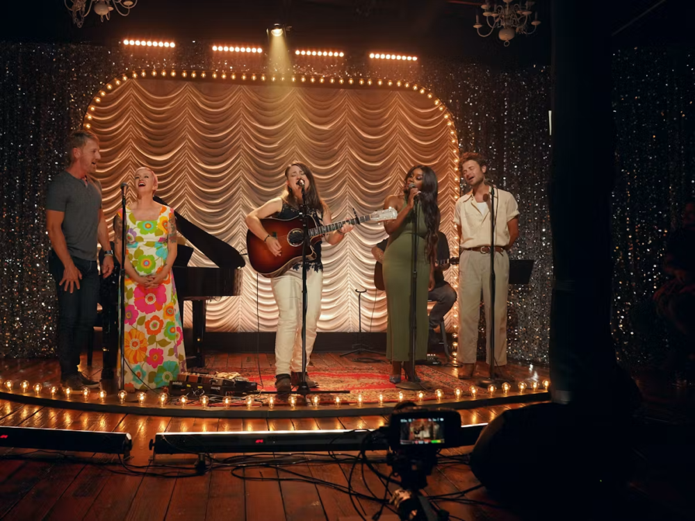 Christian artists perform on a stage with a piano and sparkly backdrop.