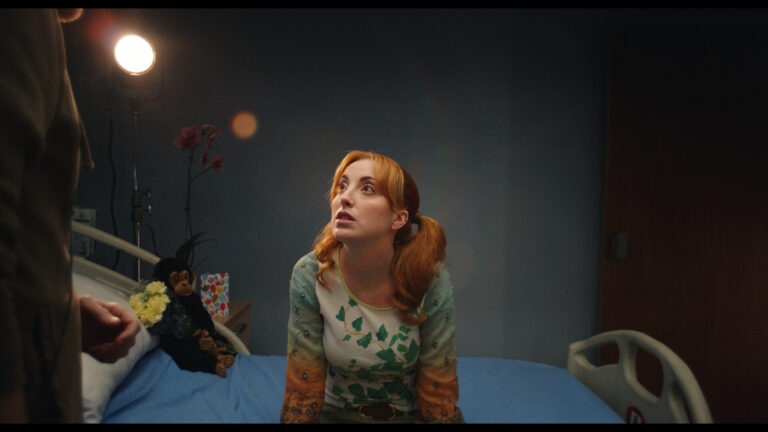Woman with red pigtails in hospital bed looks up fearfully