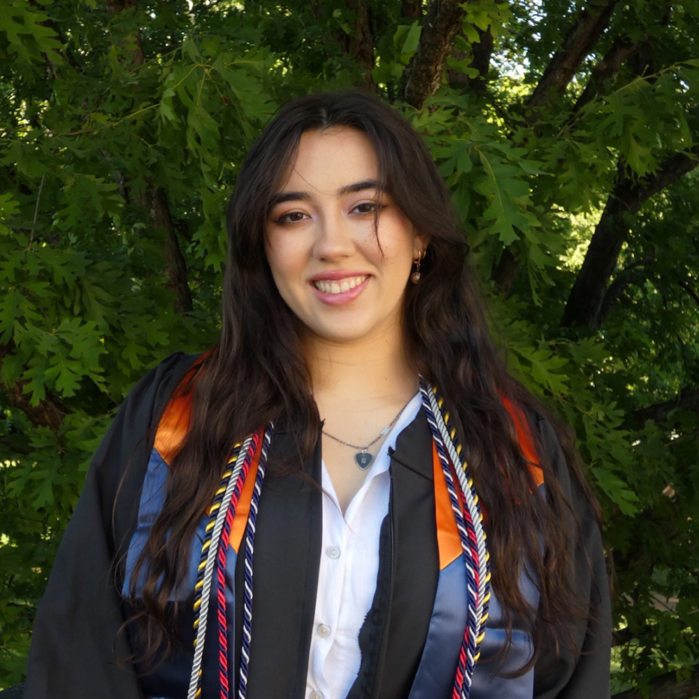 Annamaria Lund in graduation regalia, smiling outdoors.