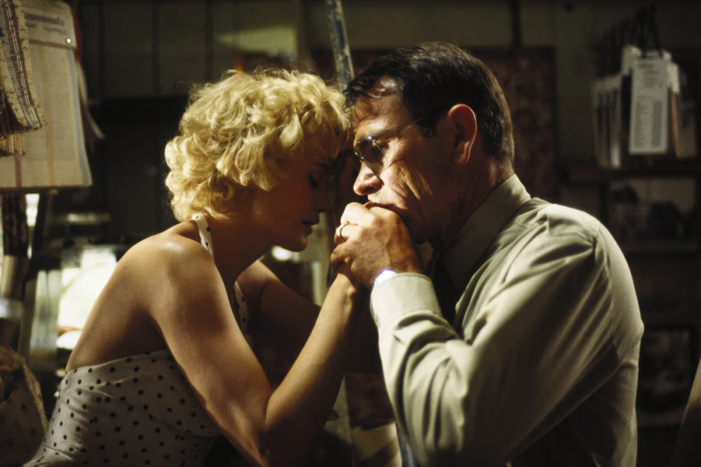 Couple embracing, foreheads touching, holding hands in a dimly lit room