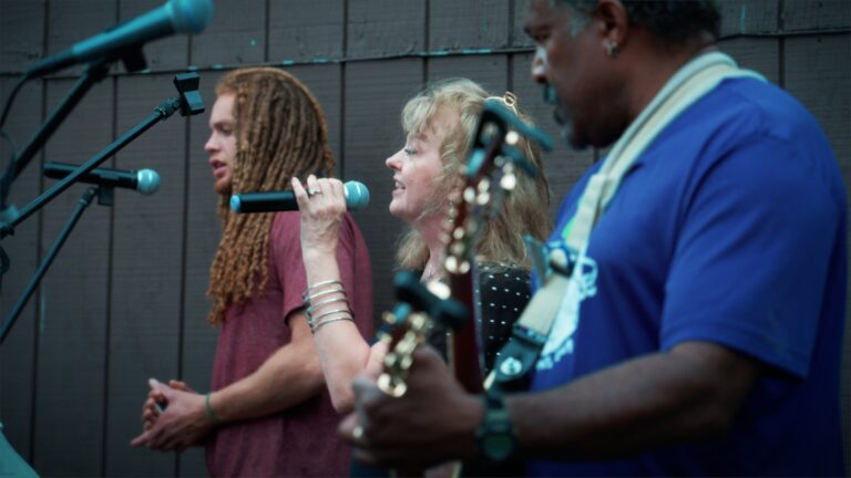 Bicycle, The Band performing live with microphones and guitars.