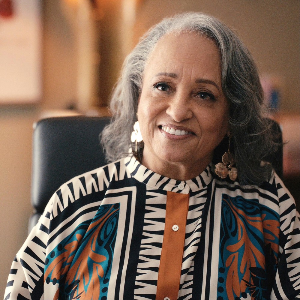 Daphne Maxwell Reid smiles in a colorful patterned top.