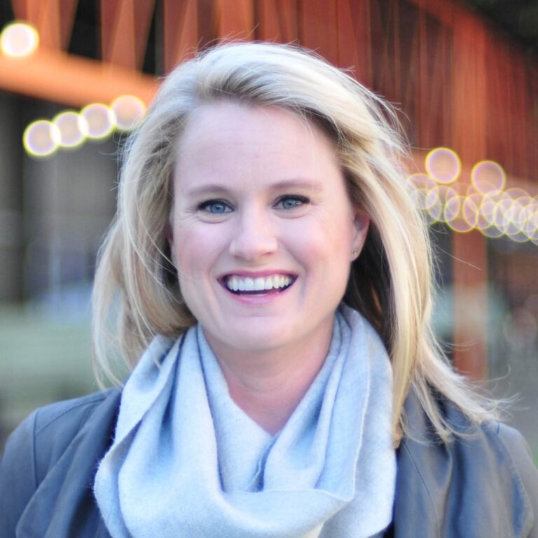Din Blankenship smiling with a light blue scarf and grey jacket