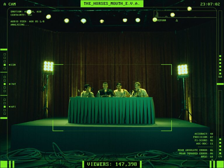 Four itchy boys on stage, facing a table with a green tablecloth.