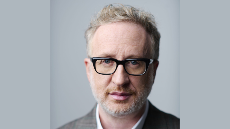 Filmmaker James Gray wearing glasses and a suit