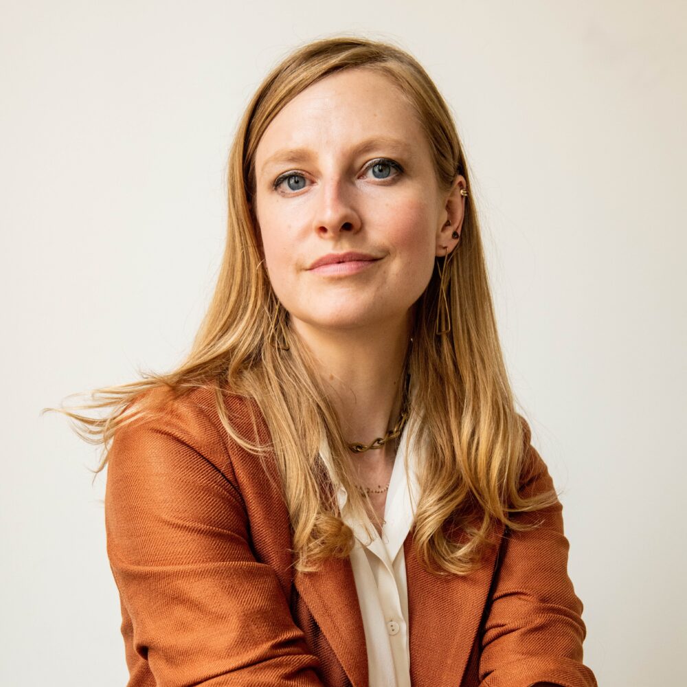 Jessica Harrop, a blonde woman with blue eyes, wears a rust-colored blazer.