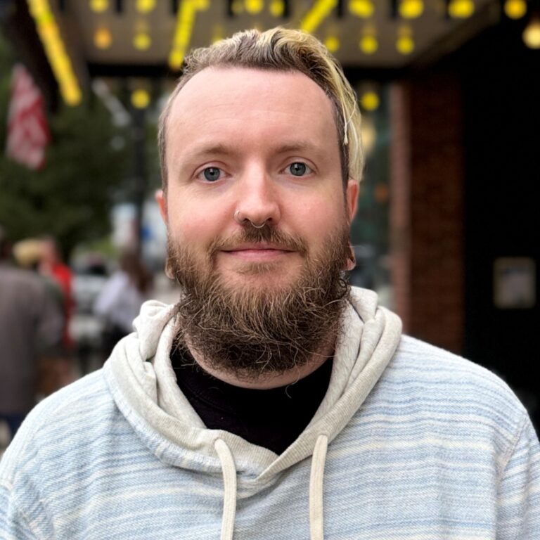 Kyle Johnson with beard and nose ring, wearing a light blue hoodie.