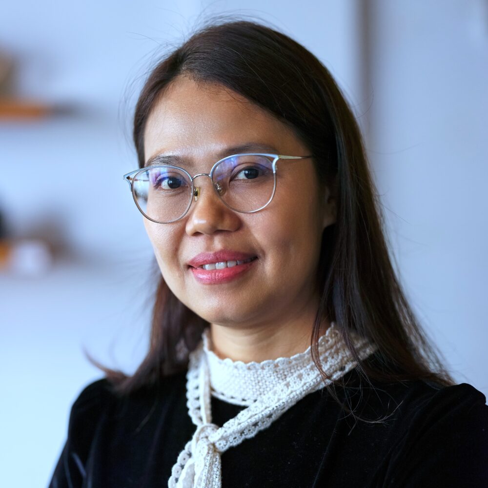 Portrait of Lê Vân, a woman wearing glasses and a black dress with white trim.
