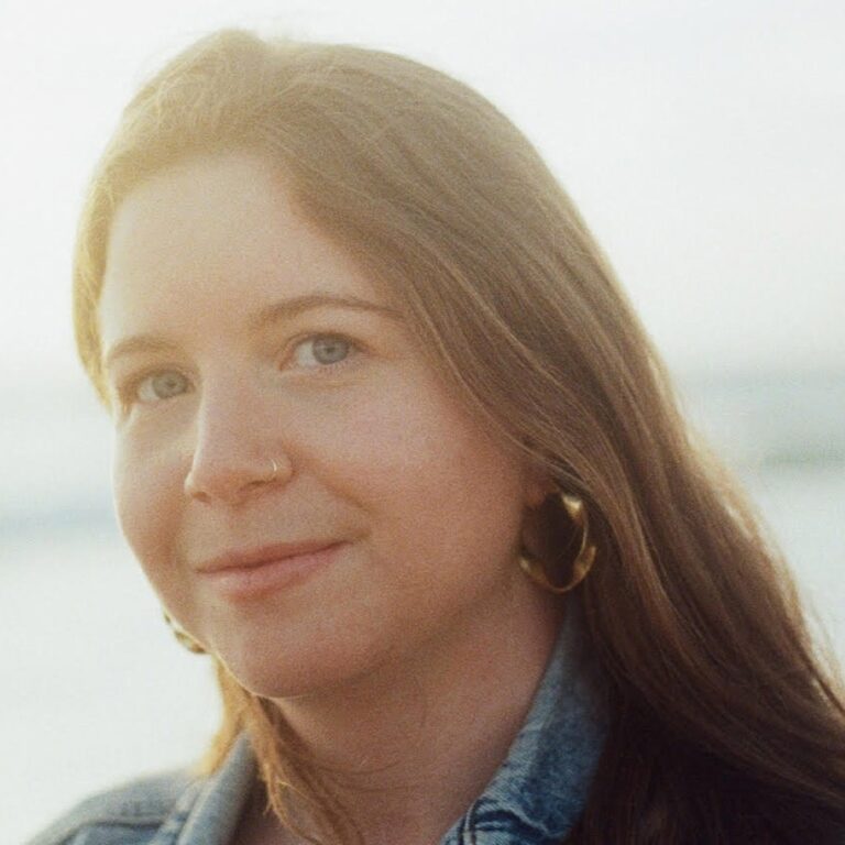 Leah Galant, a young woman with long brown hair and hoop earrings, smiles gently.