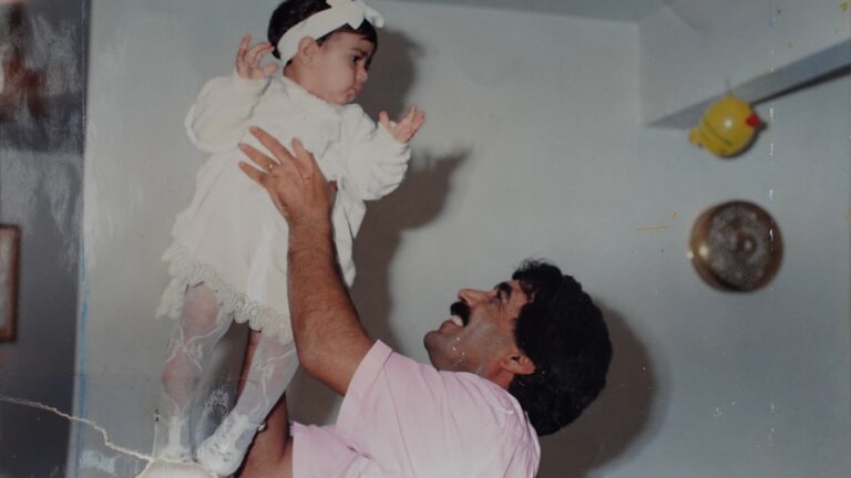 Father holding baby daughter in the air, smiling