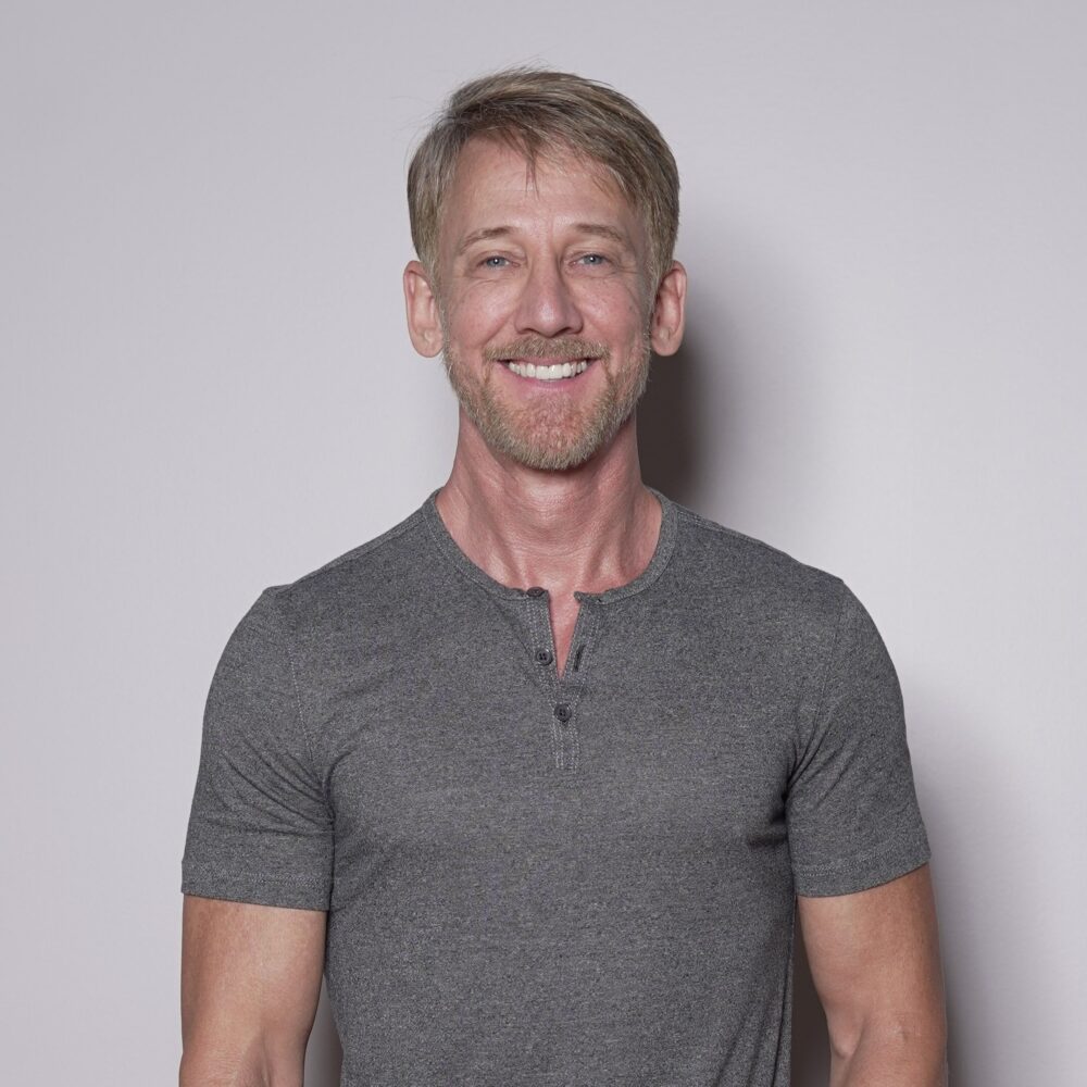 Michael Passons smiling confidently in a grey henley shirt