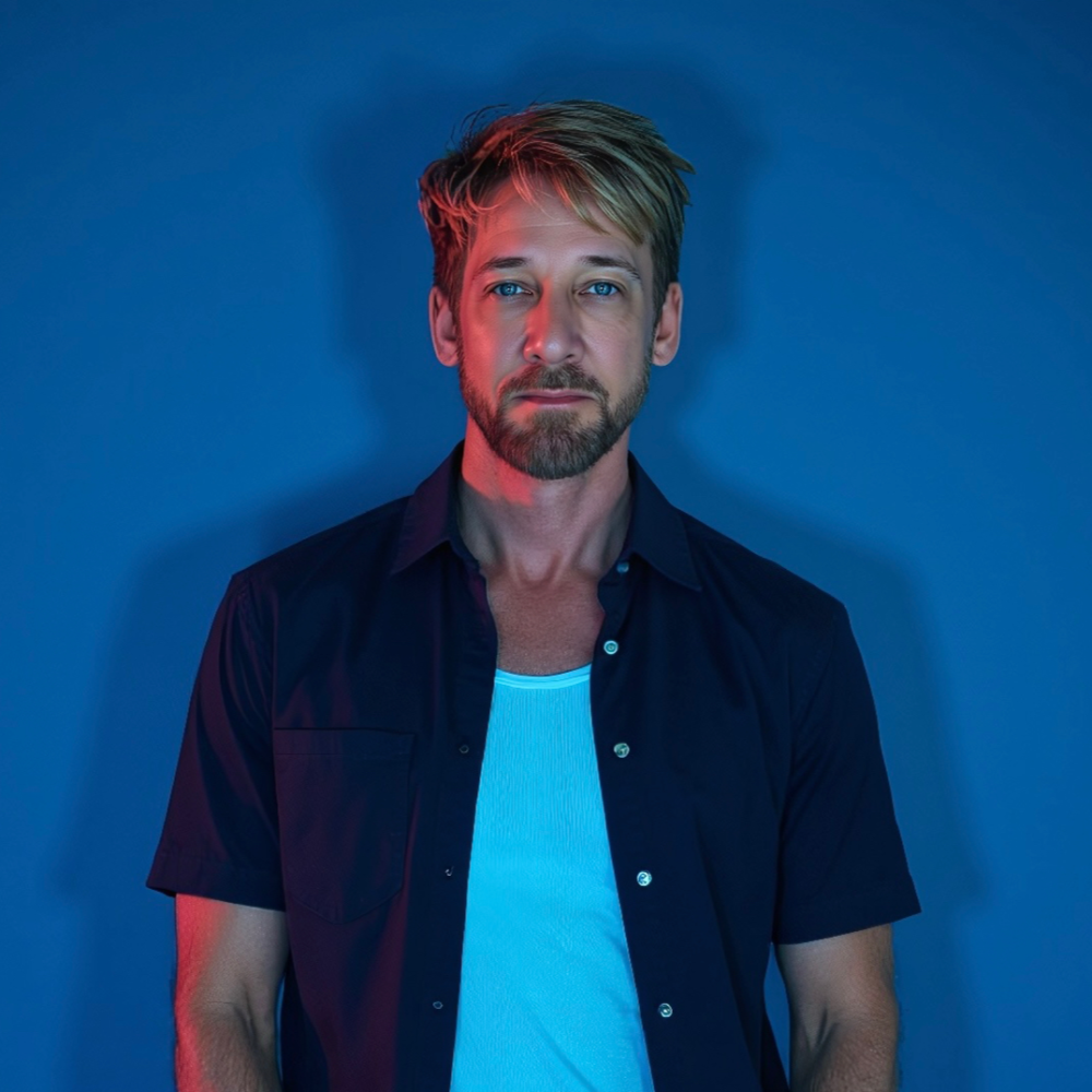 Michael Passons with blue eyes and beard, lit by blue and red light