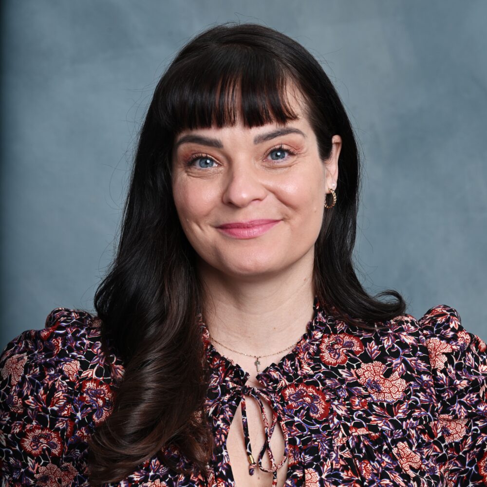 Portrait of Penny Lane, a woman with dark hair and blue eyes, smiling