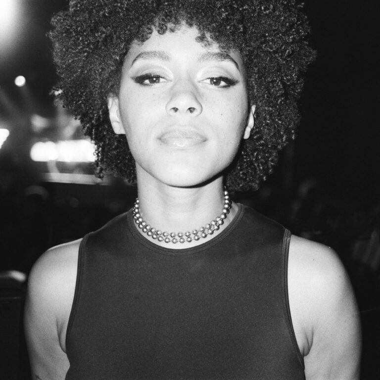 Quinn Whitney Wilson with curly hair and a beaded necklace