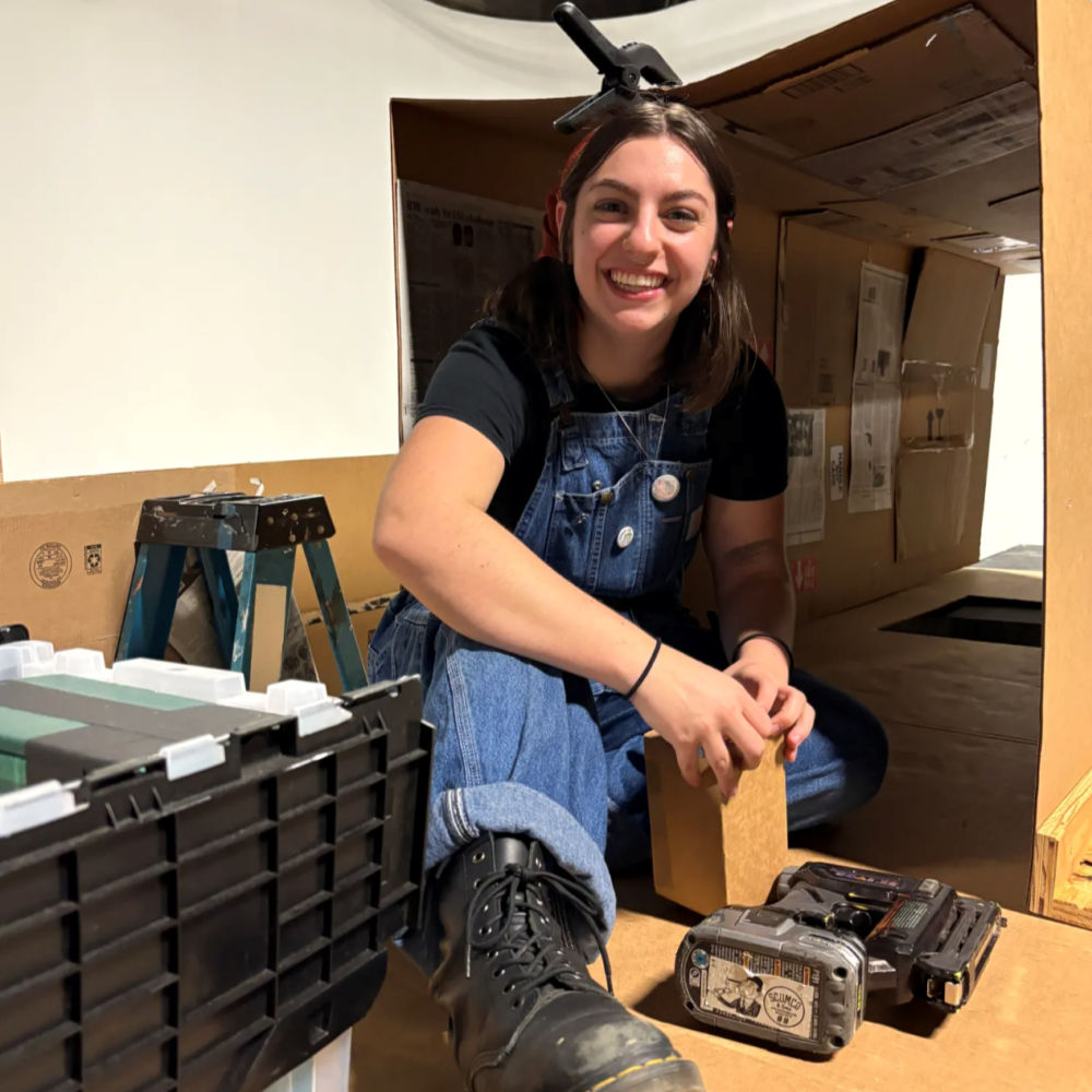 Rebecca Gendron in a cardboard fort with film equipment.