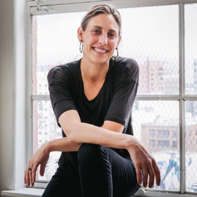 Ruth De Jong, smiling, sits by a window.