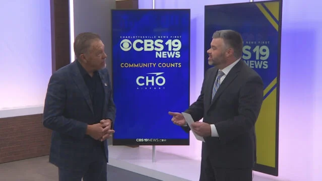Two men in suits in front of a CBS 19 News screen