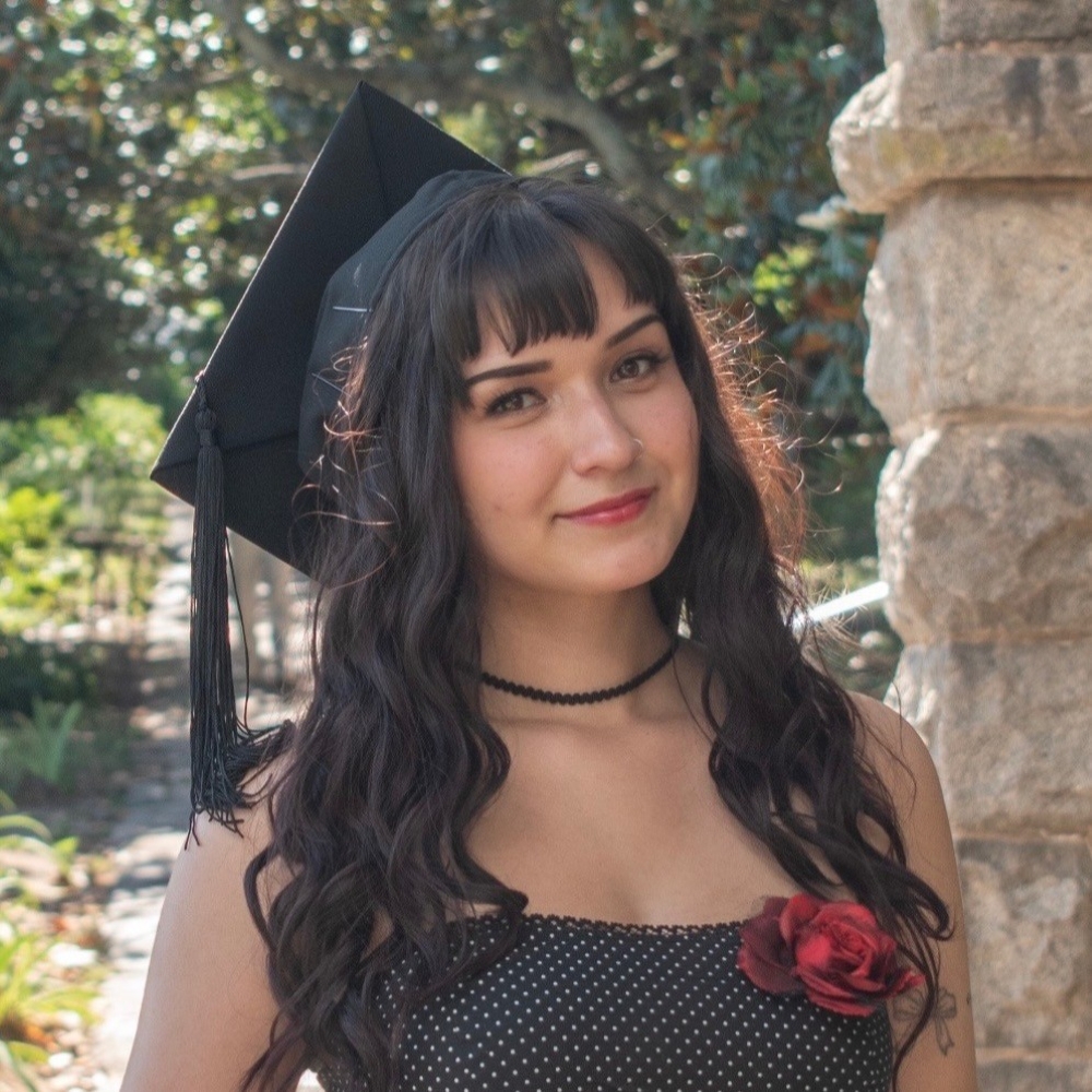 Bella Thakkar wearing a graduation cap and smiling outdoors