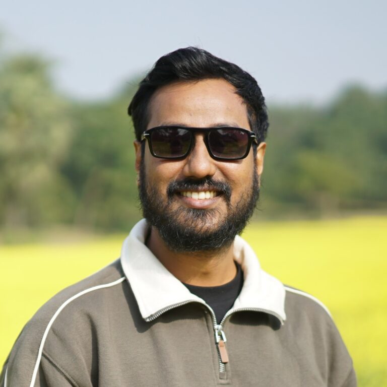 Mohammad Touqir Islam smiling in sunglasses with a blurred yellow field background.